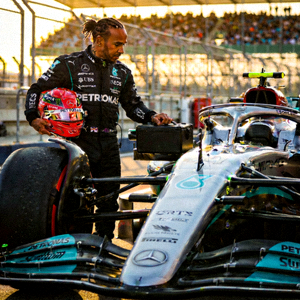 F1世界冠军刘易斯·汉密尔顿站在赛车旁，手持头盔的英姿